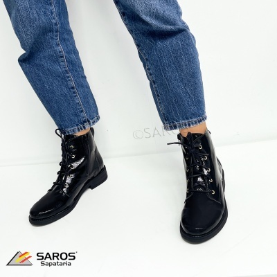 Botas pretas brilhantes com atacadores pretos e jeans azuis num fundo branco