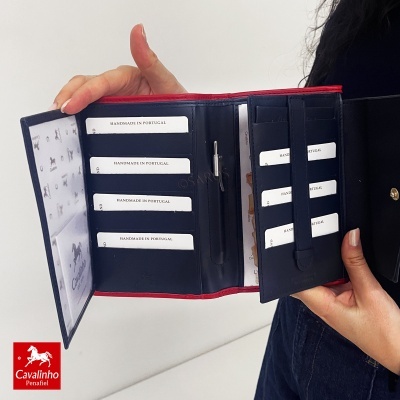 Carteira feminina em pele azul escuro com bordas vermelhas e múltiplos compartimentos para cartões.
