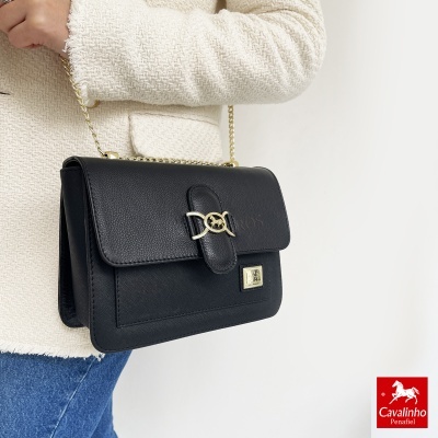 Mala preta em pele com fecho dourado e correntes douradas com casaco bege texturizado e ganga azul