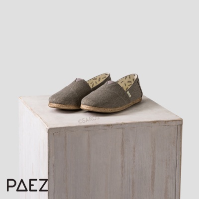 Alpercatas de tecido cinza sobre cubo de madeira clara com logo PAEZ