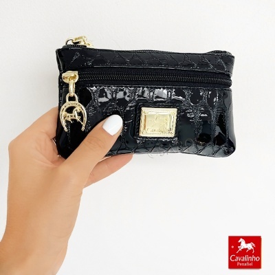 Carteira preta pequena textura croco com fecho dourado e placa metálica, com fundo branco