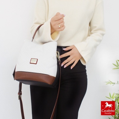 Mala branca e castanha Cavalinho com alça ajustável, usada por modelo em fundo branco.