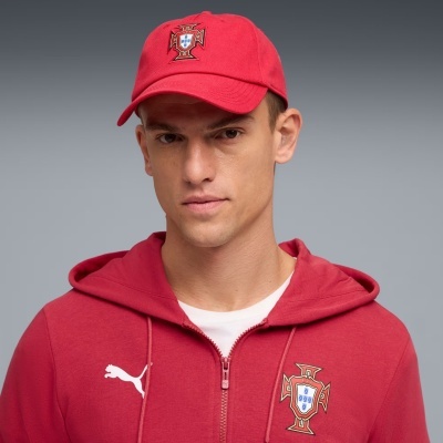 Homem com boné vermelho e casaco desportivo vermelho com brasão da cruz de Cristo e logótipo Puma