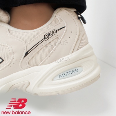 Tênis desportivo New Balance creme modelo 530 com detalhes em preto e inscrição ABZORB no calcanhar
