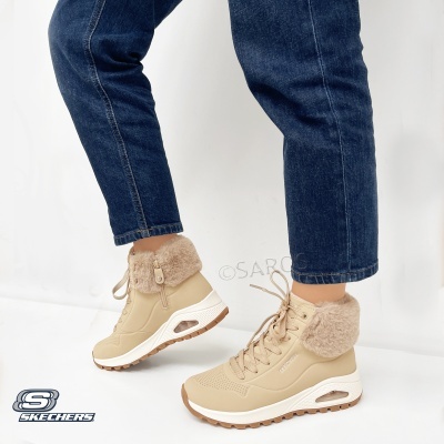 Botas bege altas com pala de pelo sintético e sola branca usadas com jeans azul escuro