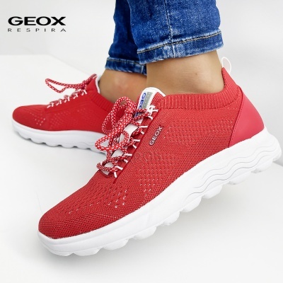 Ténis vermelhos Geox com sola branca em tecido respirável e calças de ganga azul.