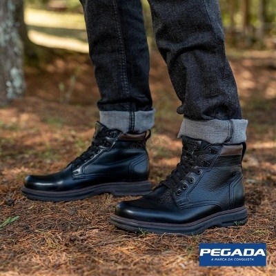 Botas de cano alto em pele preta com detalhe castanho no colarinho usadas com calças pretas num cenário exterior