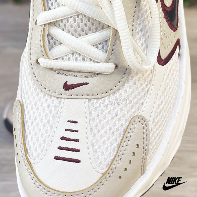 Tênis desportivo Nike branco com detalhes em bege e vinho, fabricado em malha e couro.