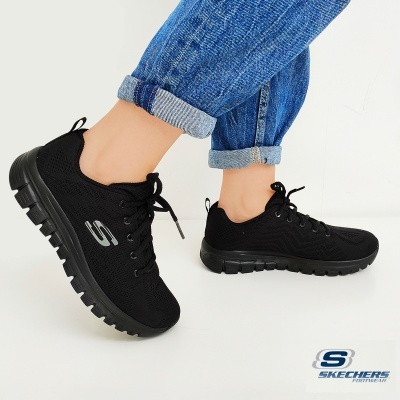Ténis pretos Skechers com sola grossa e calças de ganga azul