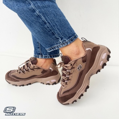 Ténis Skechers castanho com sola robusta usados com jeans azuis