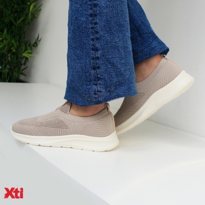 Sapatos desportivos Xti bege claro com sola branca usados com jeans azuis