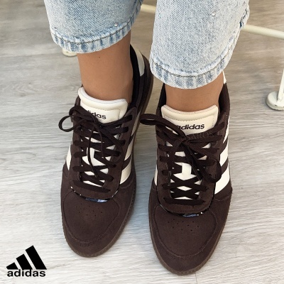 Ténis Adidas castanhos e brancos com atacadores castanhos usados com jeans azuis