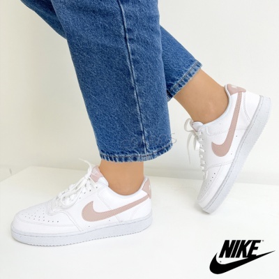 Ténis Nike Air Force 1 brancos com swoosh rosa claro usados com calças de ganga azuis