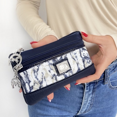 Carteira pequena azul escuro com padrão marmoreado e fecho de correr nas mãos de uma pessoa