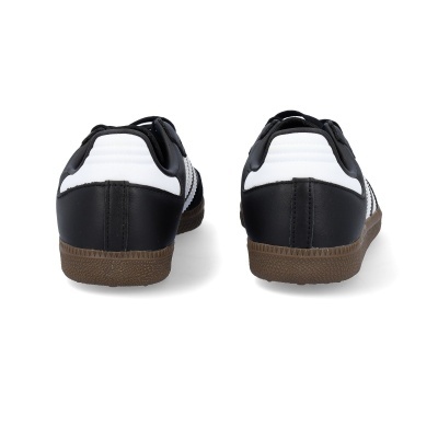 sapatos desportivos pretos com detalhes brancos e sola castanha vistos de trás