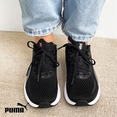 Ténis pretos Puma com sola branca usados com calças de ganga claras