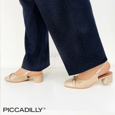 Sapatos de salto médio bege com decoração metálica usados com calças azul-escuras