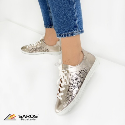 Sapatilhas douradas e bege SAROS com atacadores brancos usadas com calças de ganga