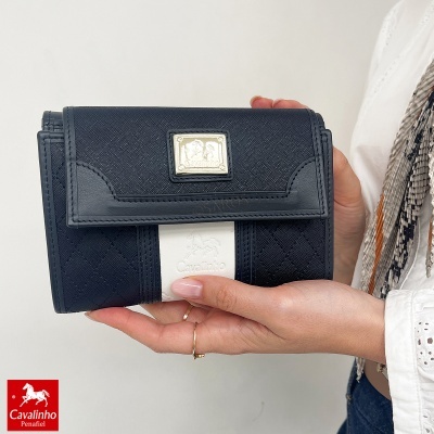 Carteira preta e branca da marca Cavalinho com textura matelassê segurada por mão feminina