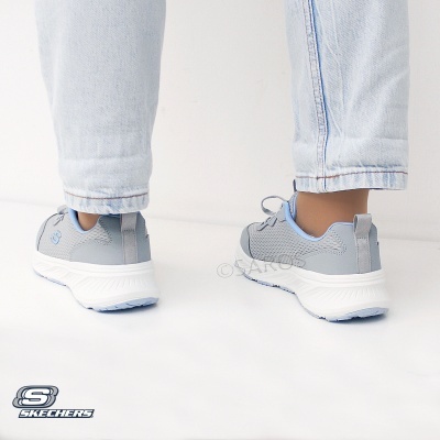 Ténis desportivos Skechers cinza com sola branca usados com calças de ganga