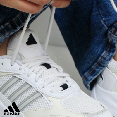 Sapatilhas desportivas brancas Adidas com detalhes cinzentos usadas com calças de ganga azuis