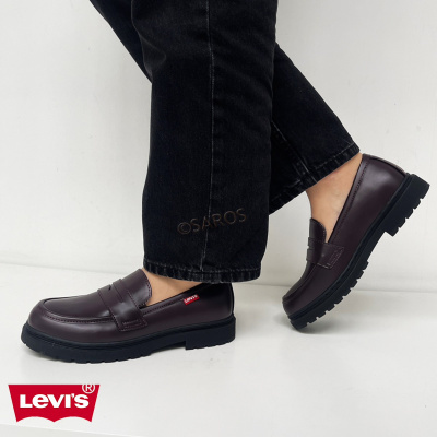 Sapatos Levis castanhos escuros com sola preta e etiqueta vermelha, usados com calças pretas