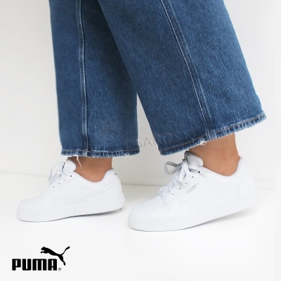 Ténis brancos PUMA com sola branca usados com calças de ganga azuis