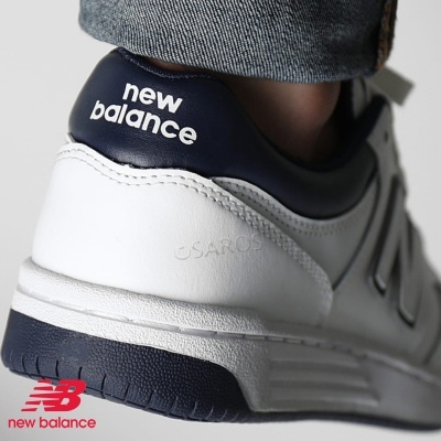 Sapatilha desportiva New Balance branco e azul-marinho com texto no calcanhar