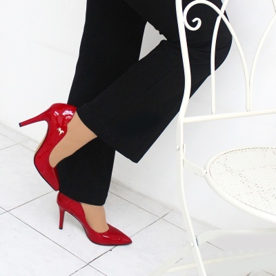 Sapatos de salto alto vermelhos em verniz junto a cadeira branca