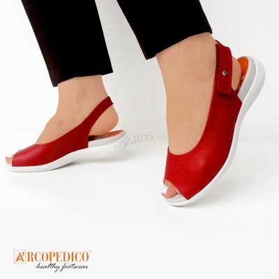 Sandálias vermelhas com sola branca e detalhe laranja no calcanhar numa pessoa com calças pretas