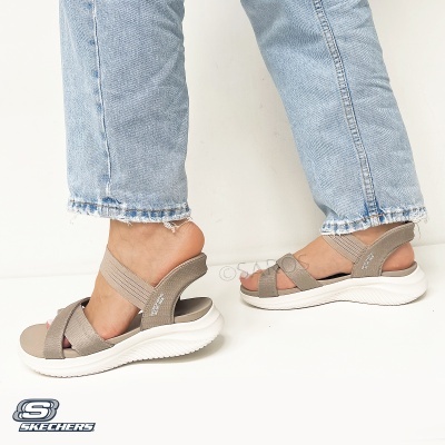 Sandálias Skechers bege com sola branca e calças de ganga azul claro.