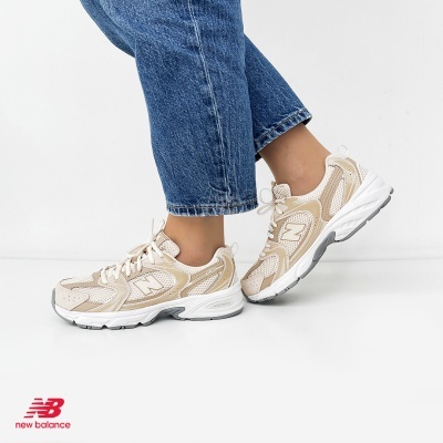 Ténis New Balance bege com branco e cinza usados com jeans azuis