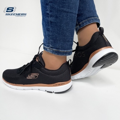 ténis Skechers pretos com detalhes rosa dourado e sola branca usados com jeans azuis