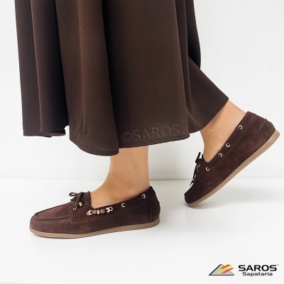 Sapatos mocassim castanhos com atacadores decorativos usados com saia castanha sobre fundo branco
