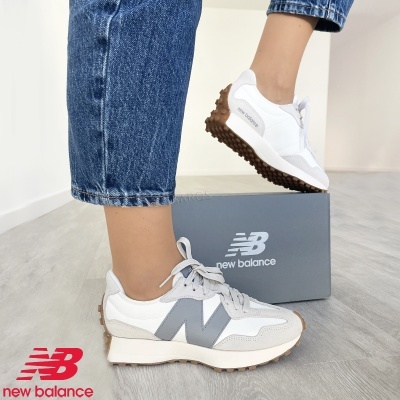 Ténis New Balance brancos e cinzentos junto a caixa cinzenta com logótipo.