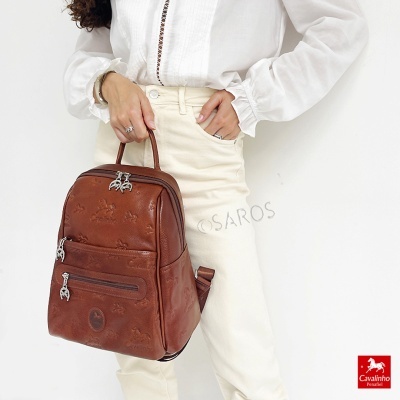 Mochila de couro castanho com padrões gravados sendo segurada por pessoa com roupa clara