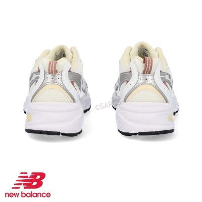 Sapatilhas New Balance vista de trás, em branco, cinza e bege, em fundo branco.