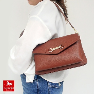 Mala castanha de pele com fecho metálico usada ao ombro