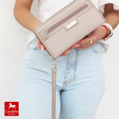 Carteira bege com fecho zip e alça de pulso segurada por pessoa
