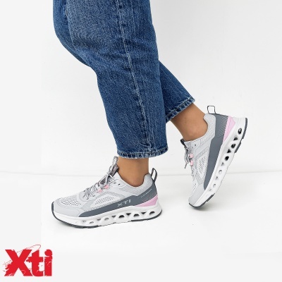 Ténis de senhora cinzentos com rosa claro e sola branca, usados com calças de ganga azul.