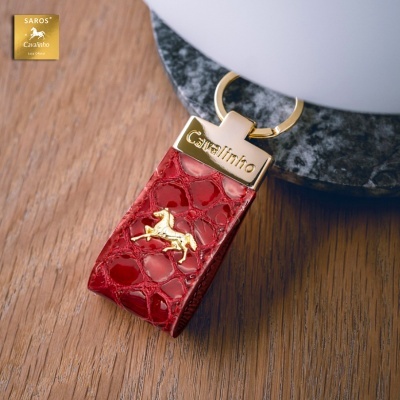 Porta-chaves de pele vermelha com textura tipo crocodilo e detalhes dourados com texto Cavalinho