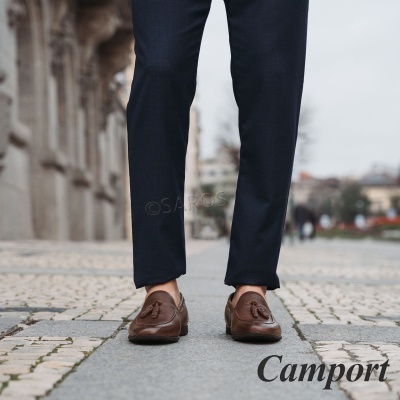 Sapatos de pele castanha com borlas e calças azul-escuras em pavimento de calçada urbana