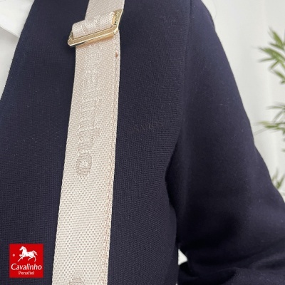 Alça bege com ajuste dourado e texto Cavalinho em casaco azul escuro