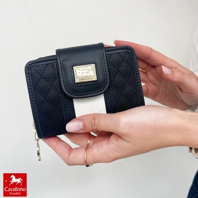 Carteira preta com faixa branca e placa dourada em mãos femininas