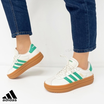 Sapatos desportivos Adidas brancos com riscas verdes e sola castanha