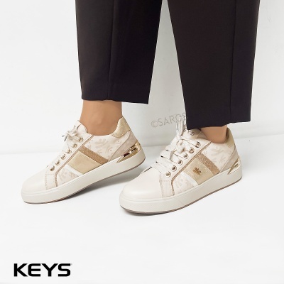 Sapatilhas brancas e douradas com padrão e atacadores brancos