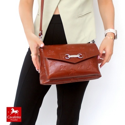 Mala castanha em pele com fecho prateado e textura de relevo, usada por modelo