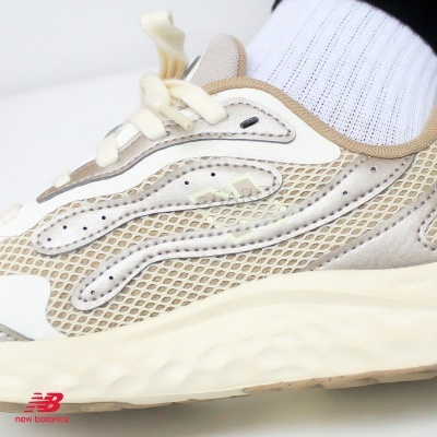 Ténis desportivos beiges New Balance com malha e camurça.