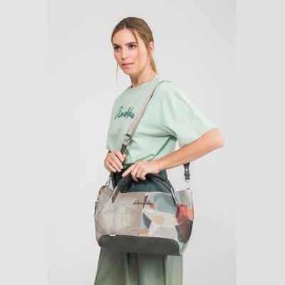 Mulher com camisola verde clara e mala de mão em padrão geométrico patchwork