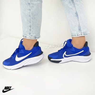 Ténis Nike azuis com logo branco e jeans claros